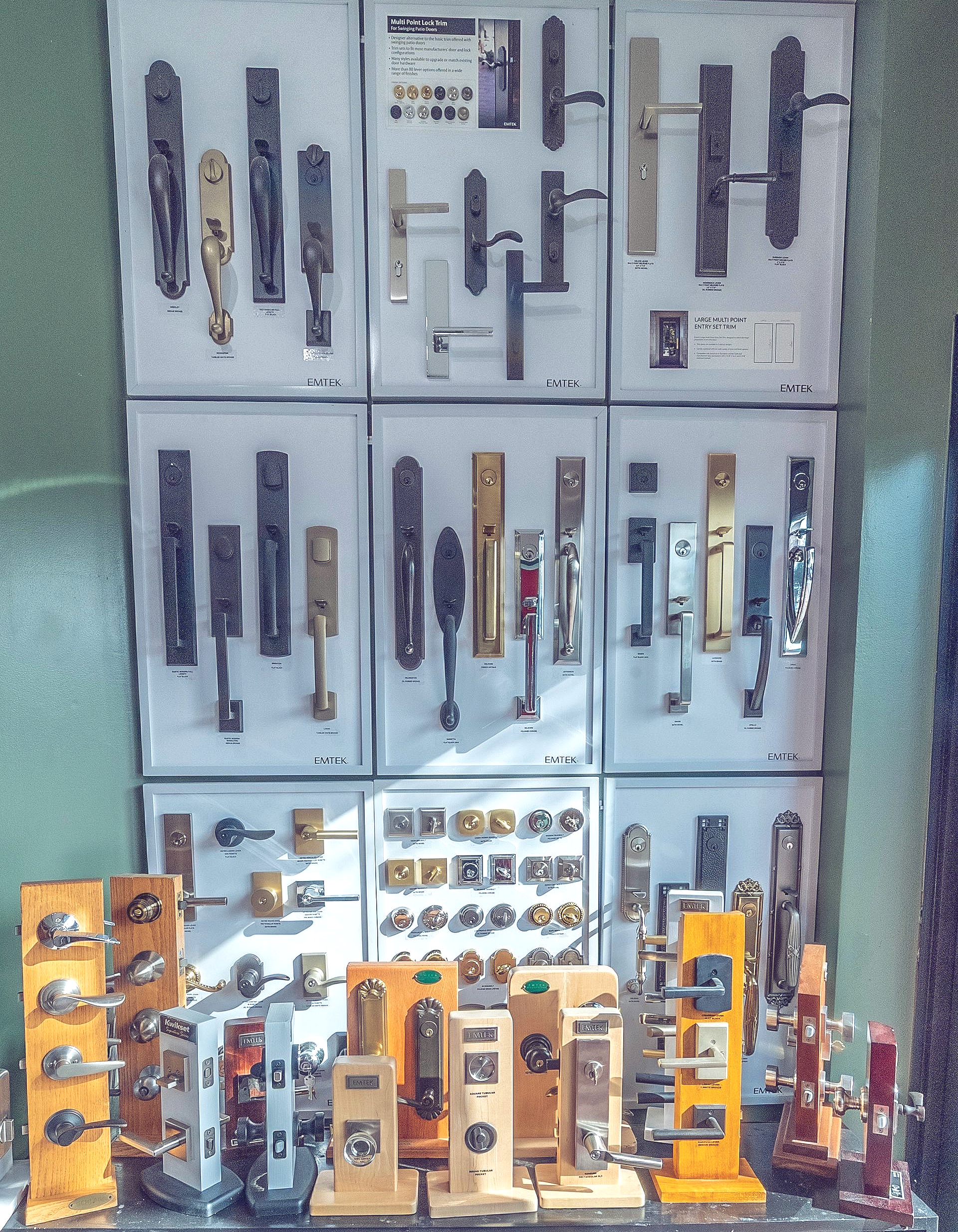Door handles and locks displayed on a wall in a store. Some on individual stands.