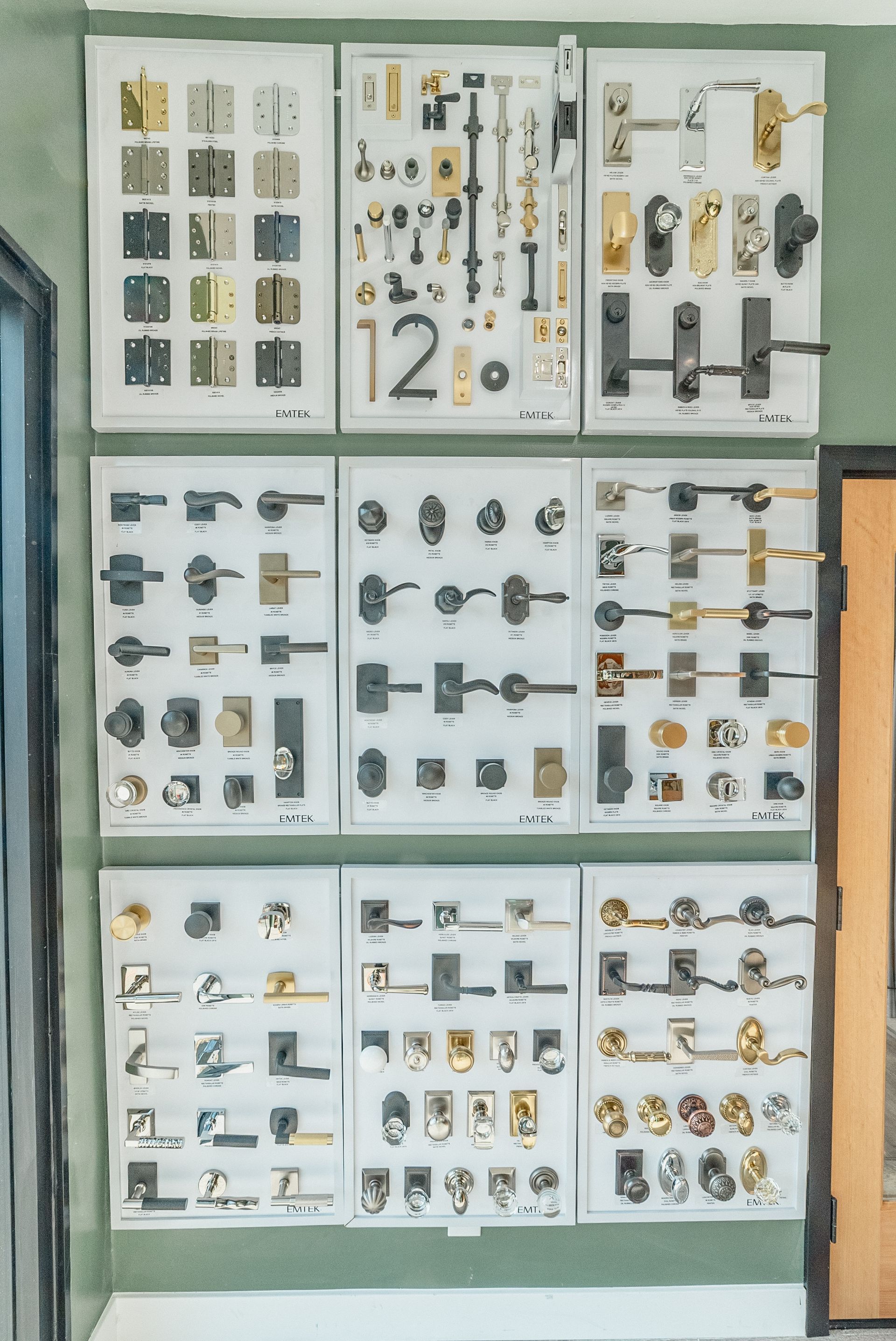 Displays of various door hardware, including handles, locks, and hinges, arranged on white boards.