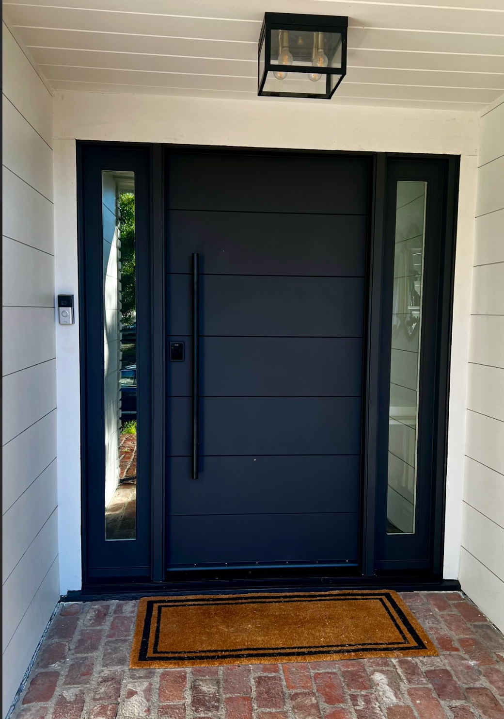 Double gray front doors with silver handles and trim, white frame, and small mailbox.
