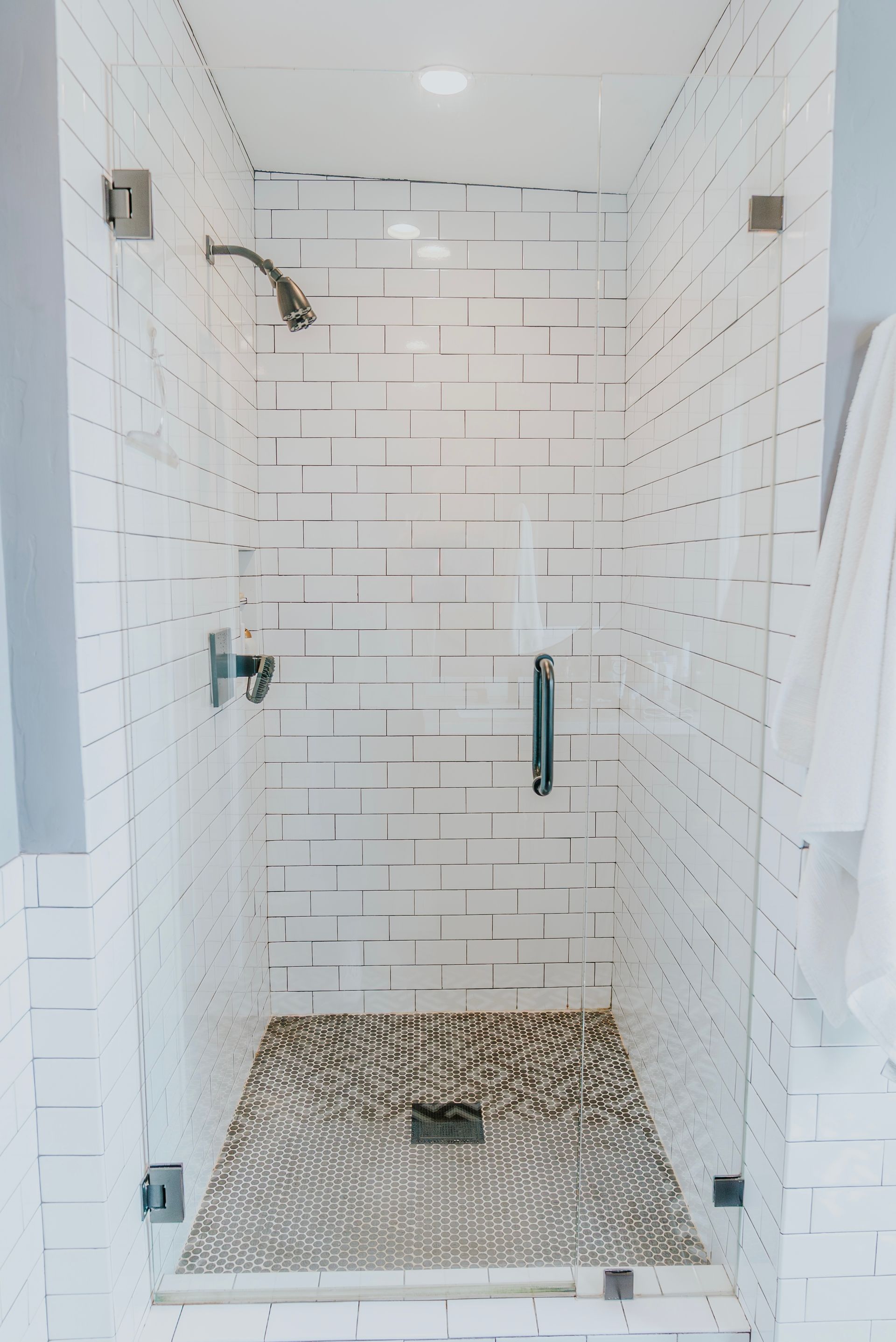 Glass shower enclosure with black metal frame, marble interior, two showerheads.