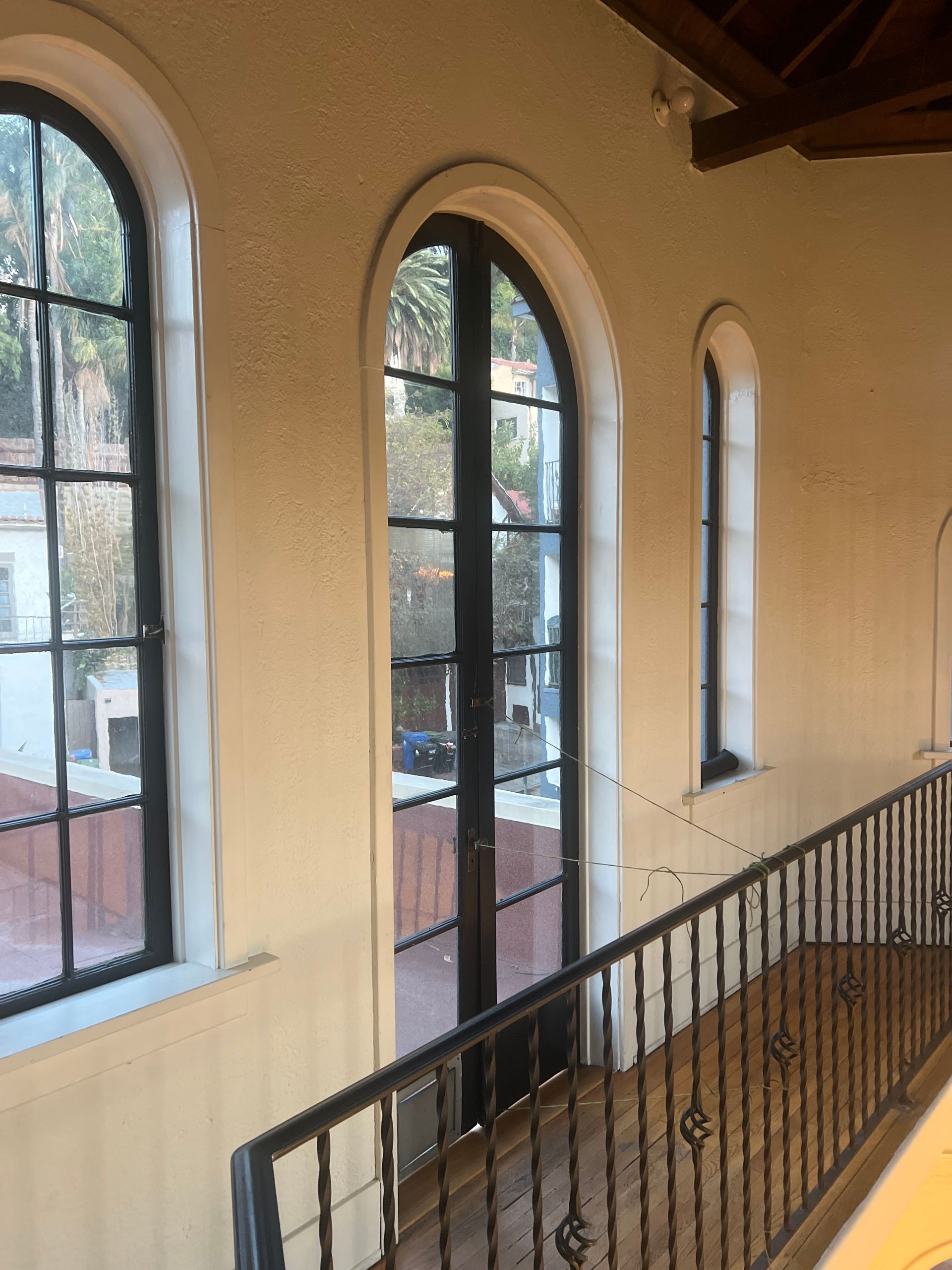 Interior view: arched windows overlooking a street, with a wrought iron railing on a balcony.