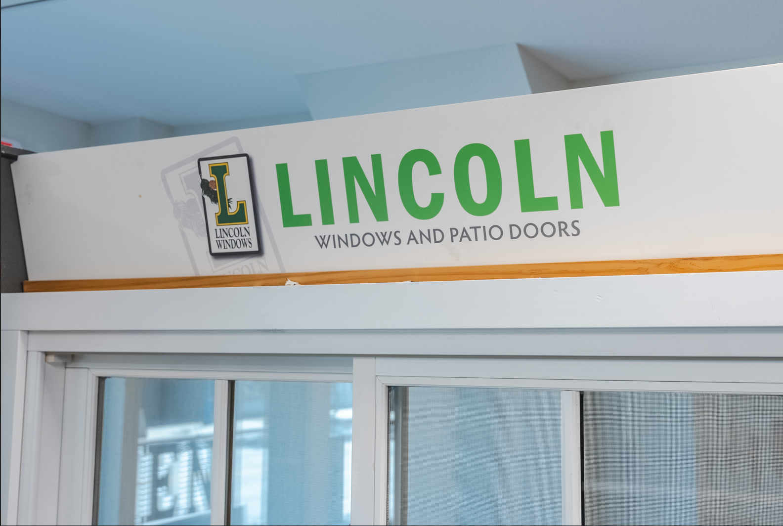 Sign for Lincoln Windows and Patio Doors above a sliding glass door.