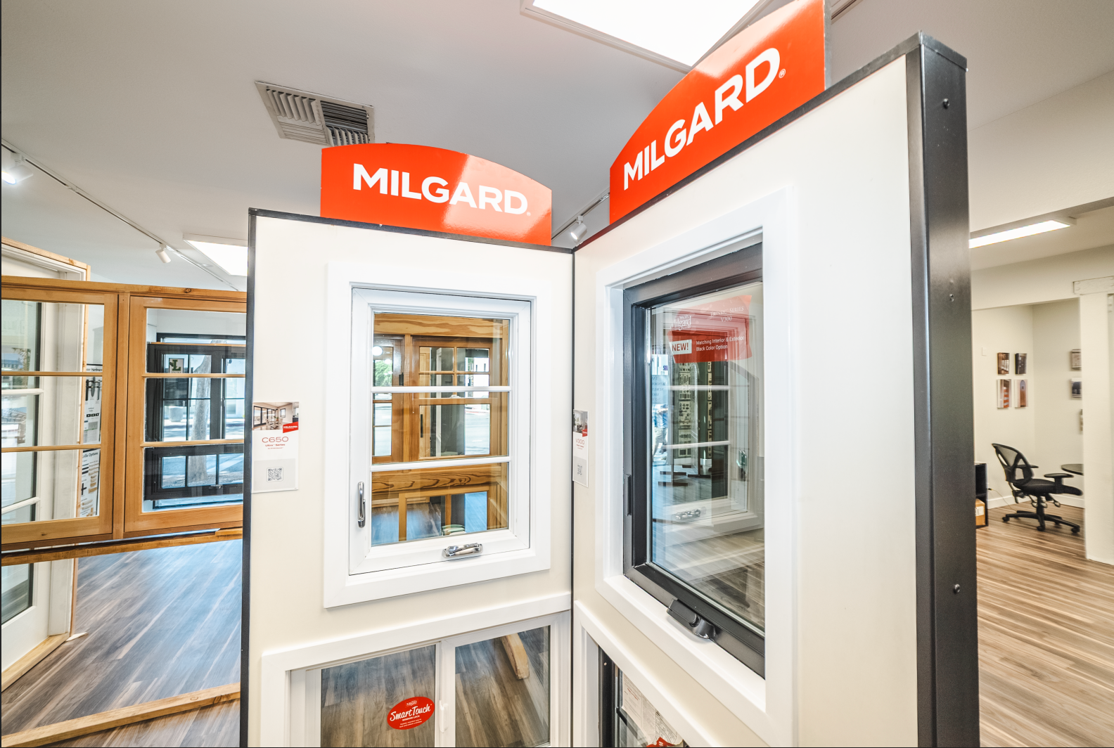 Milgard window display with various window styles in a showroom. Red Milgard logo signage.