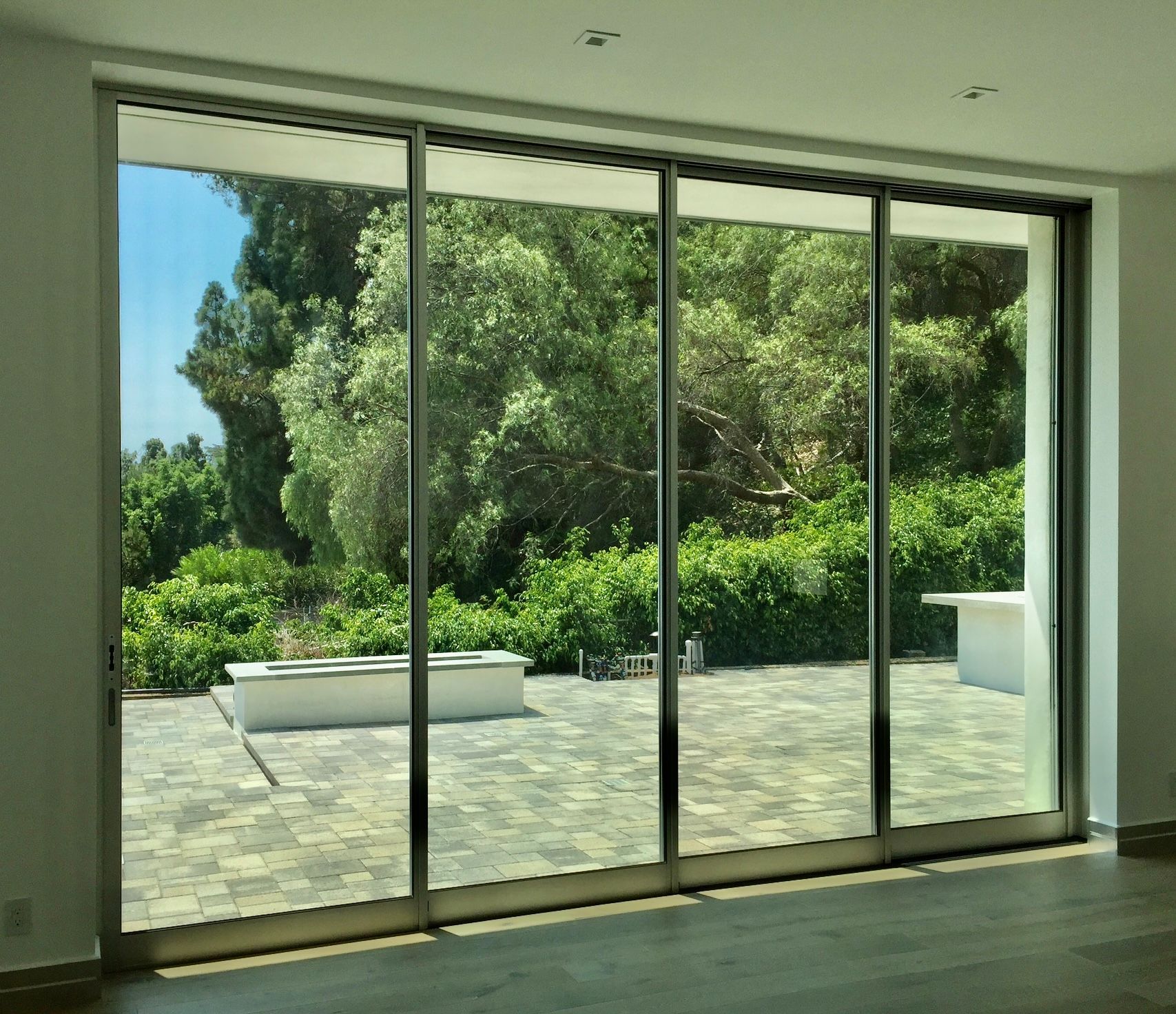 Large glass sliding doors open to a sunny patio and lush green garden.