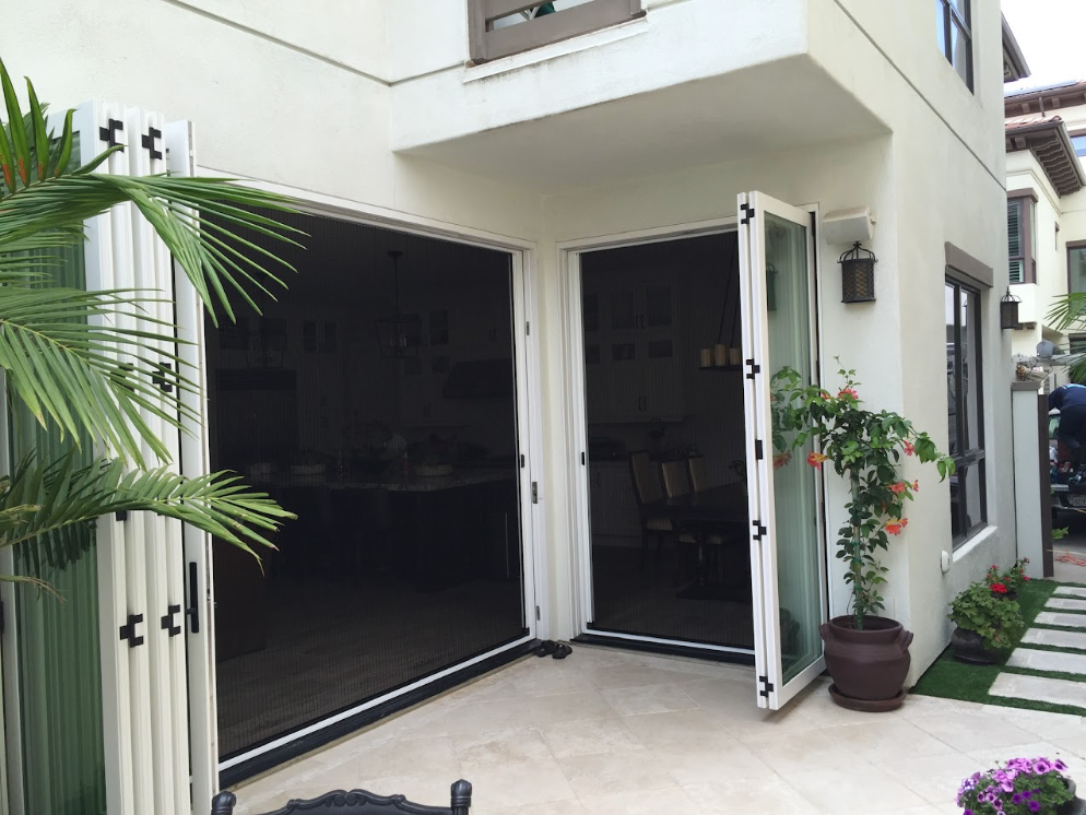 Motorized retractable screen lowering across a wide bifold opening to a pool terrace at a Beverly Hills home