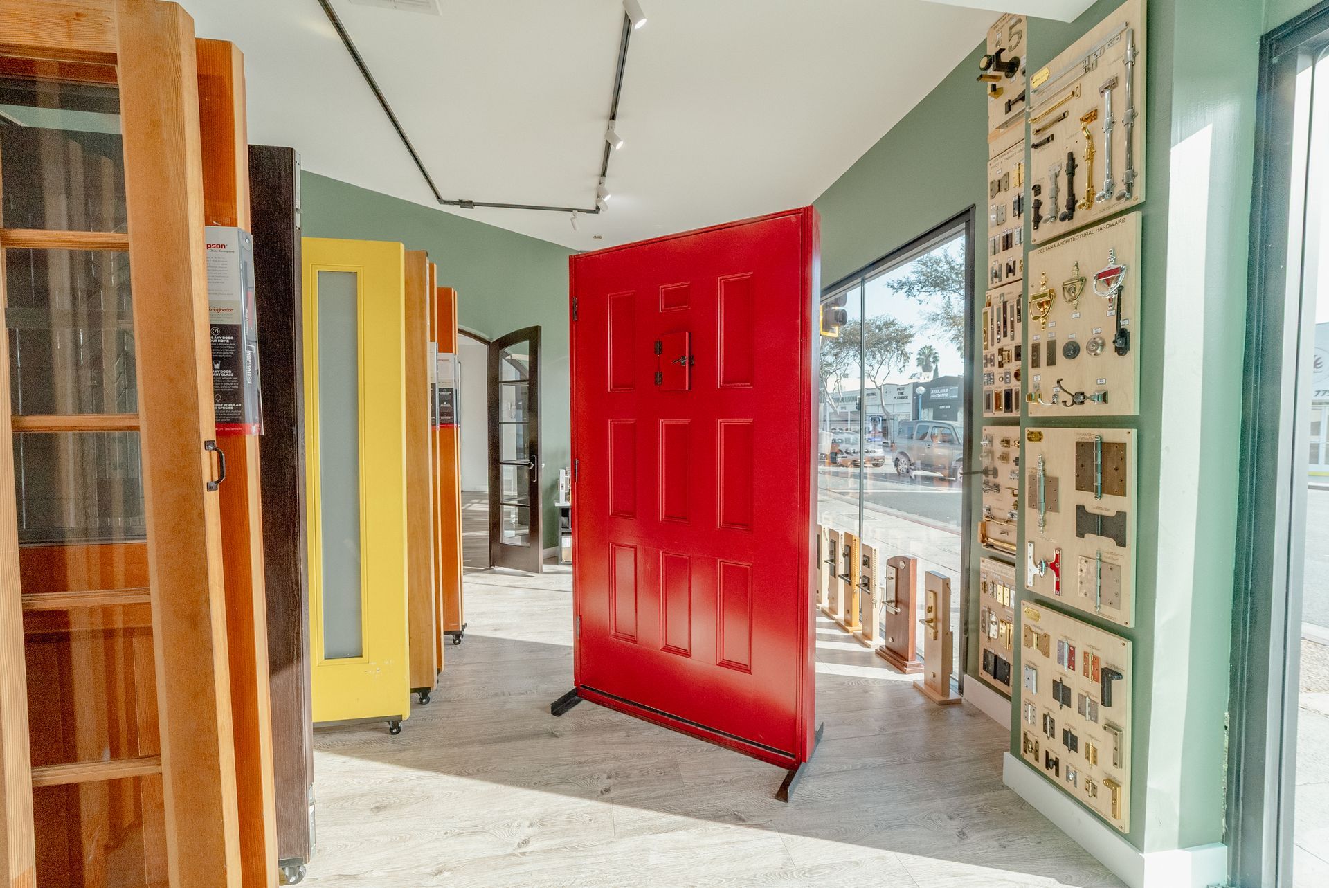 A bright red door displayed in a gallery with several other doors of varying colors.