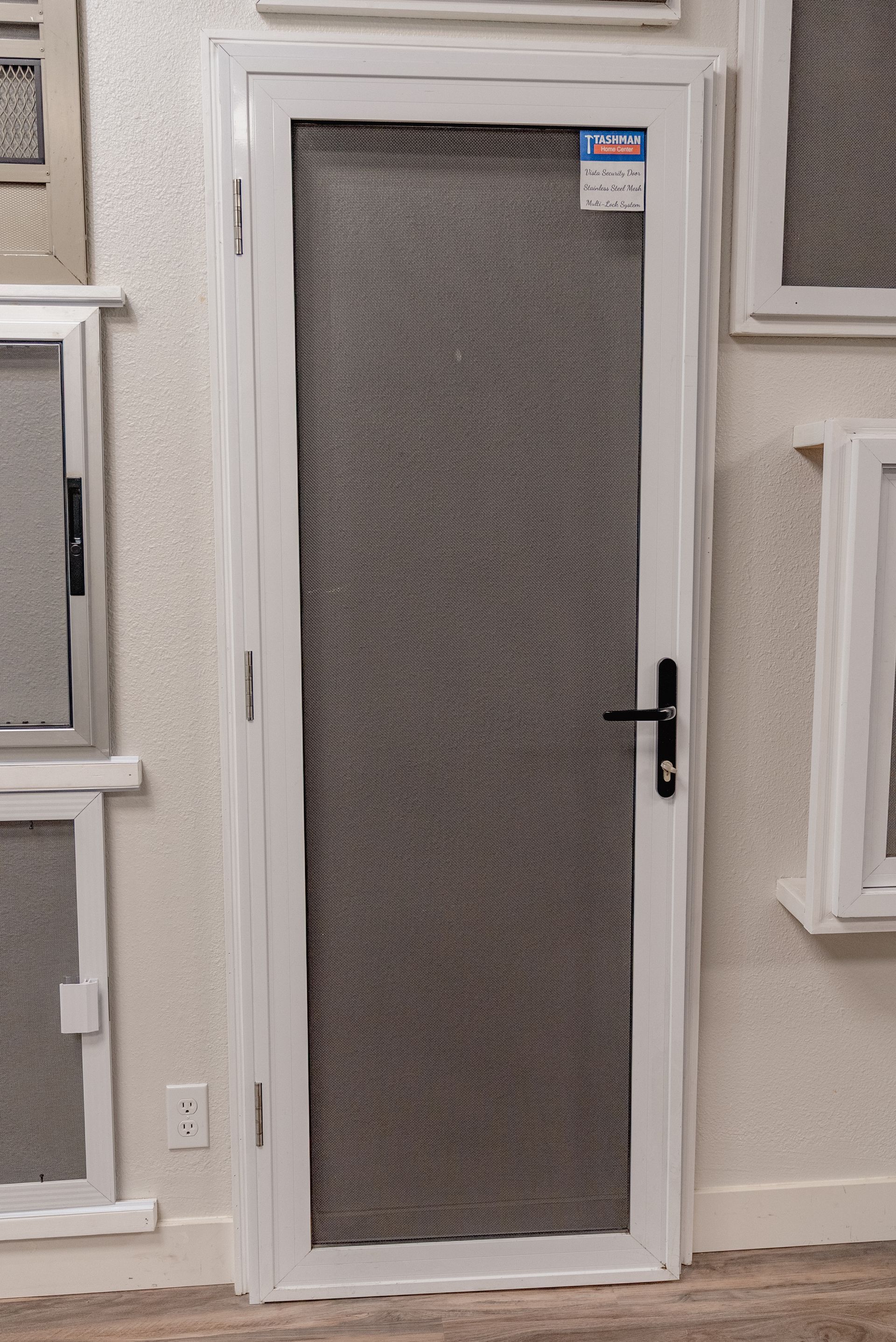 White metal screen door with black handle and gray mesh.