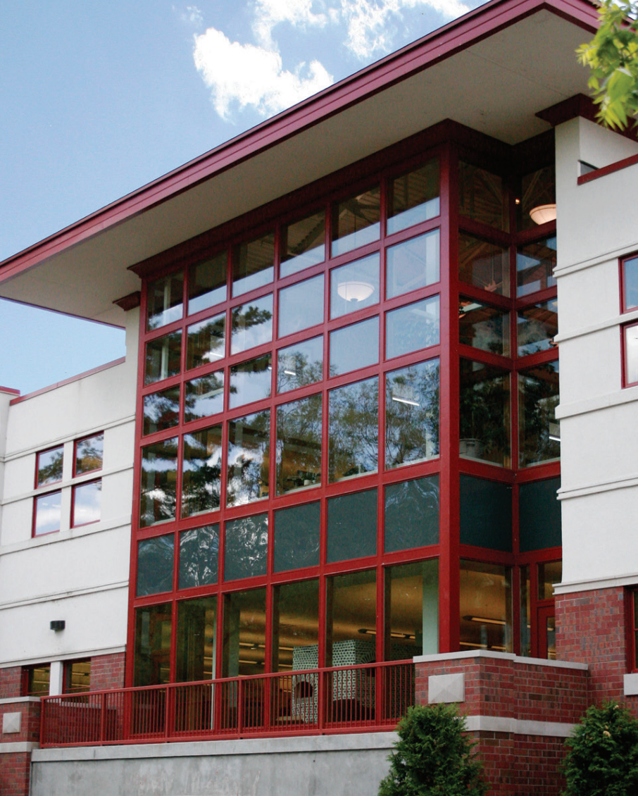 Modern building entrance with red-framed glass windows and a covered roof overhang