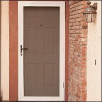 Brown door with screen, white frame, brick wall, and outdoor lamp.