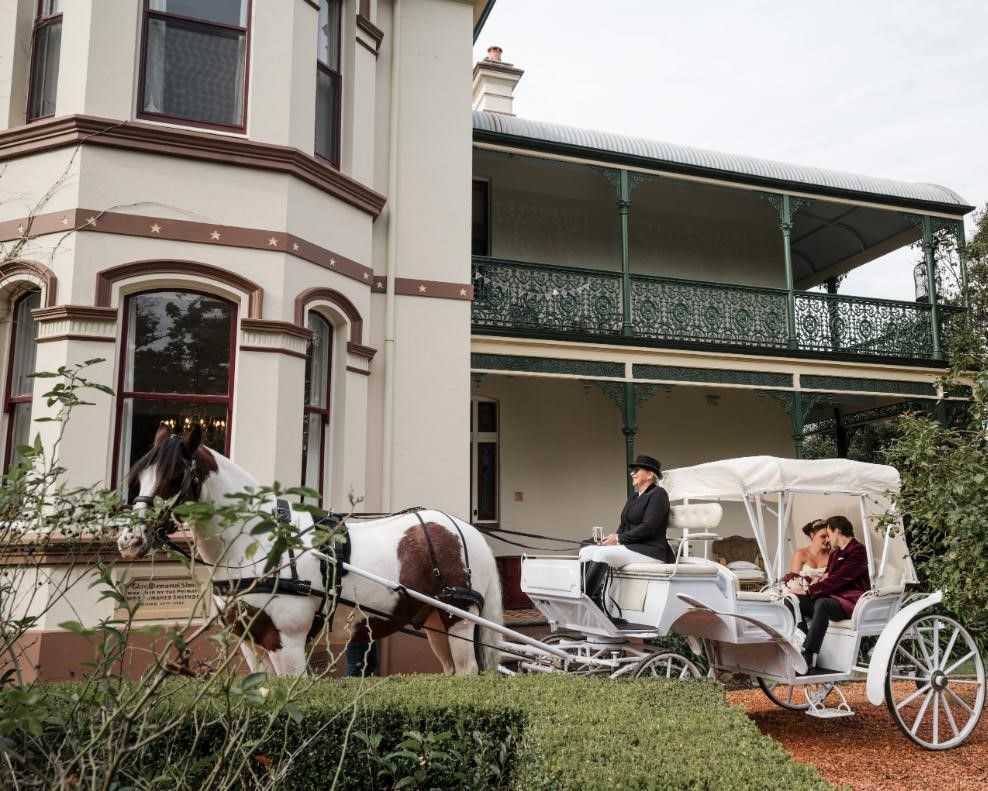 A Horse Drawn Carriage is Parked in Front of a Large White Building — Prestige Horse Carriages in Mitchells Flat, NSW
