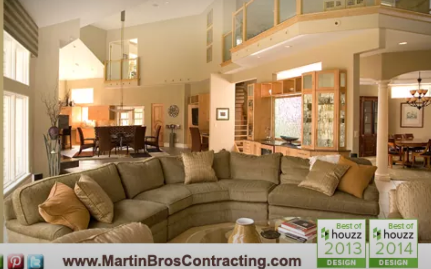 A living room with a large sectional couch and the website www.martinbroscontracting.com