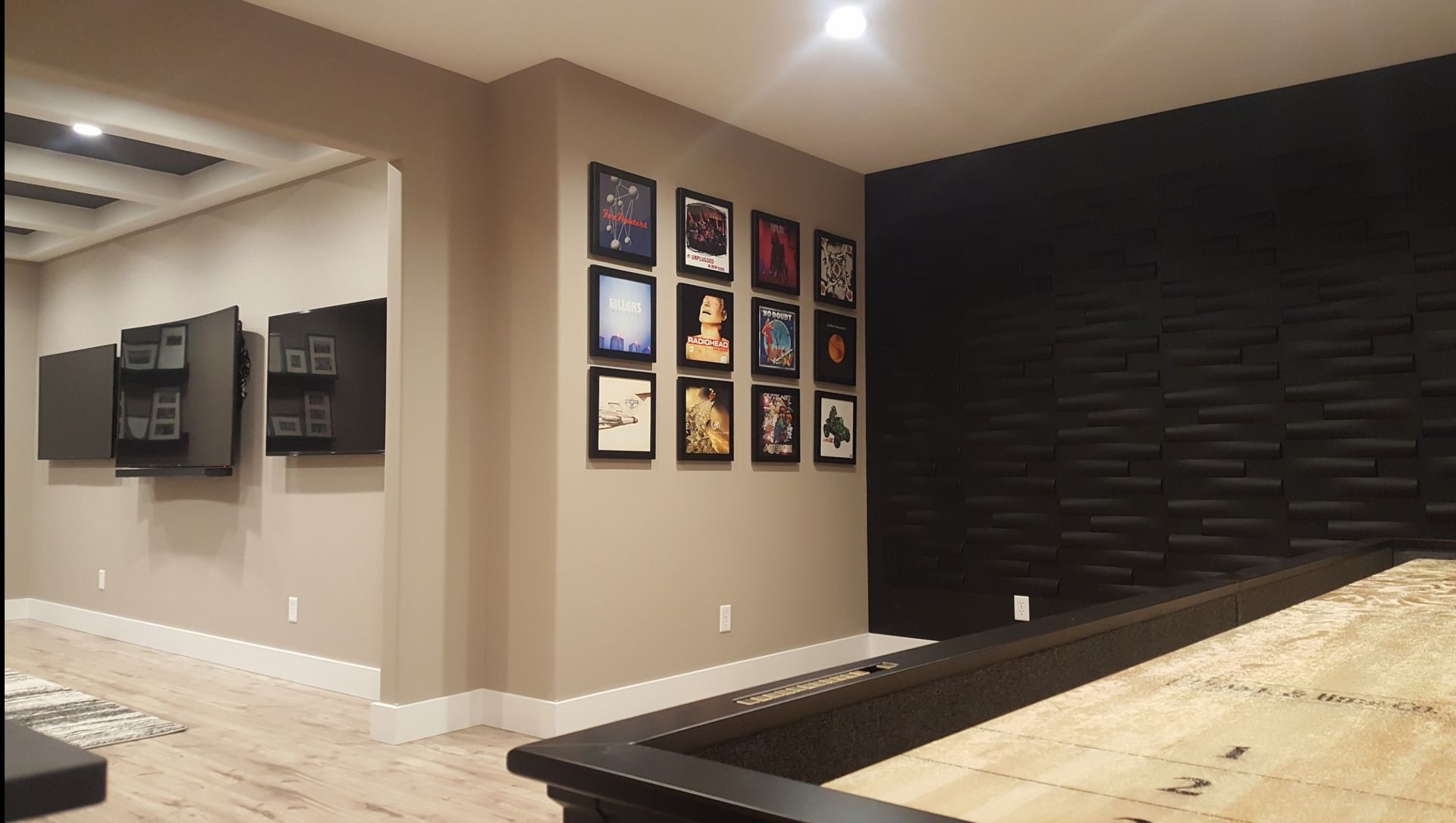 A basement with a pool table and pictures on the wall