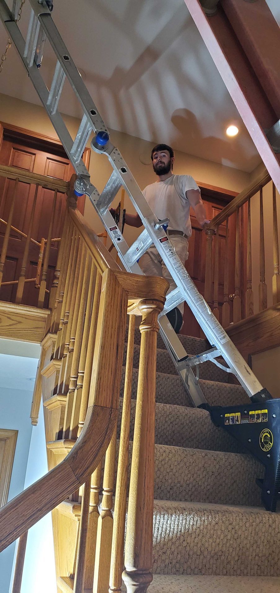 A man is standing on a ladder on top of a set of stairs.