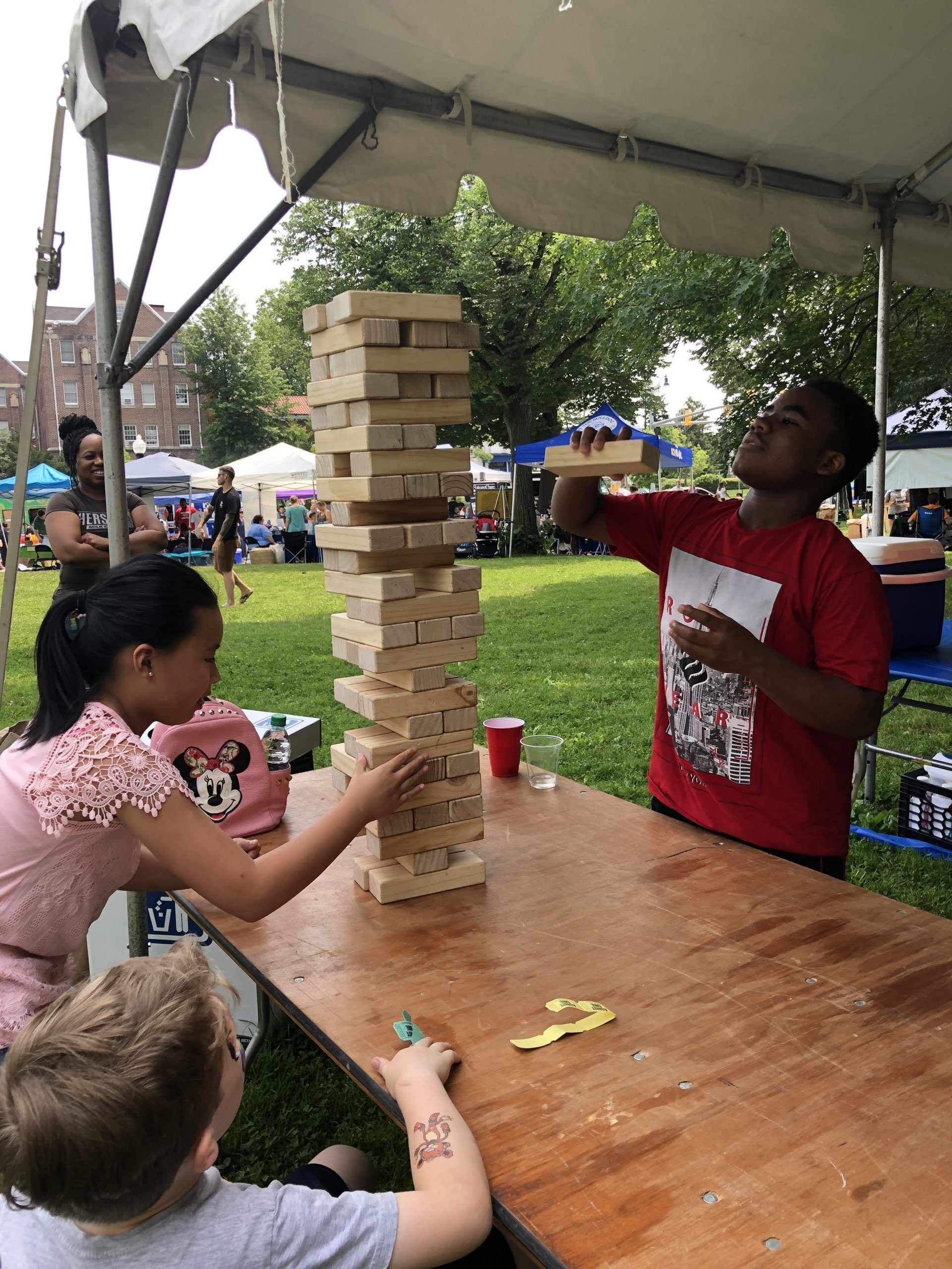A group of people are playing jenga in a park.