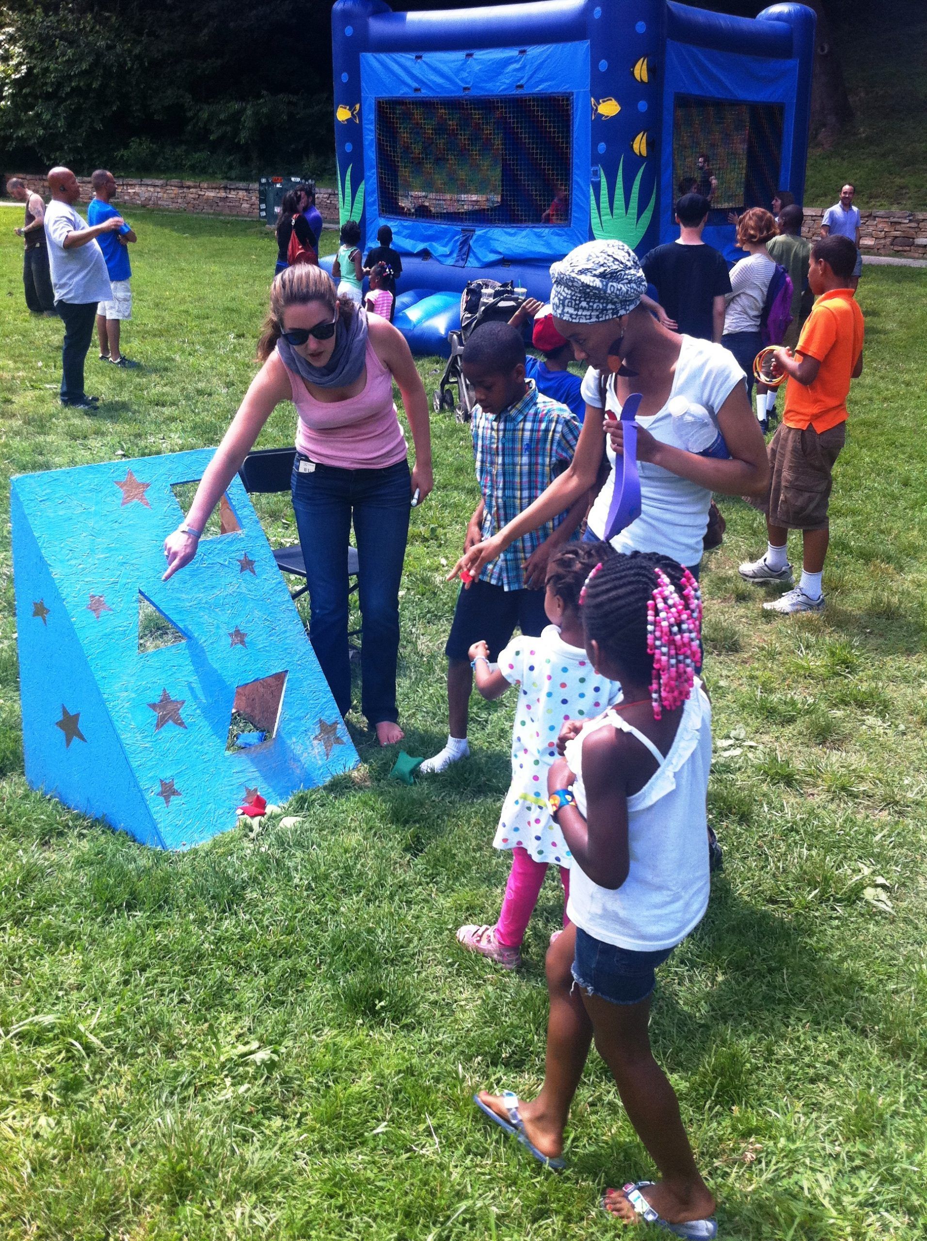 A group of people are playing a game in a park with a bouncy house in the background