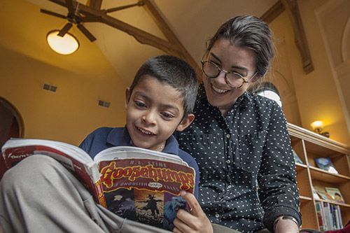 A woman is reading a book to a young boy.