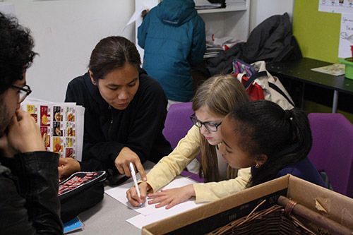A group of children are sitting around a table looking at a book.