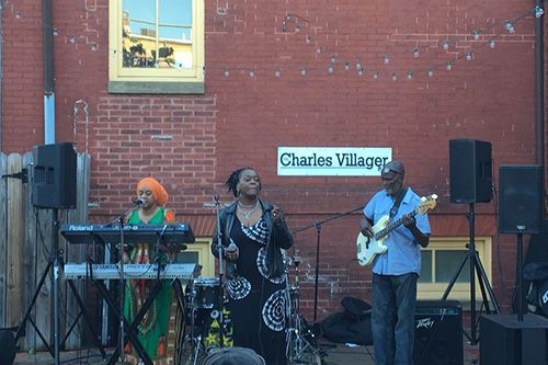 A group of people are playing instruments in front of a brick building.