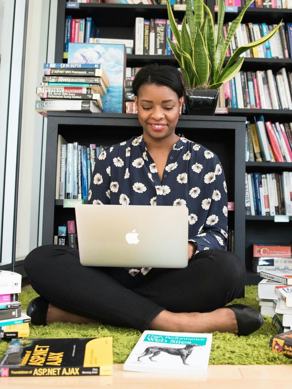 A woman is sitting on the floor using an apple laptop