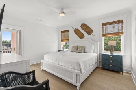 Bright white bedroom with a white bed, woven wall decor, and blue nightstands beside window blinds