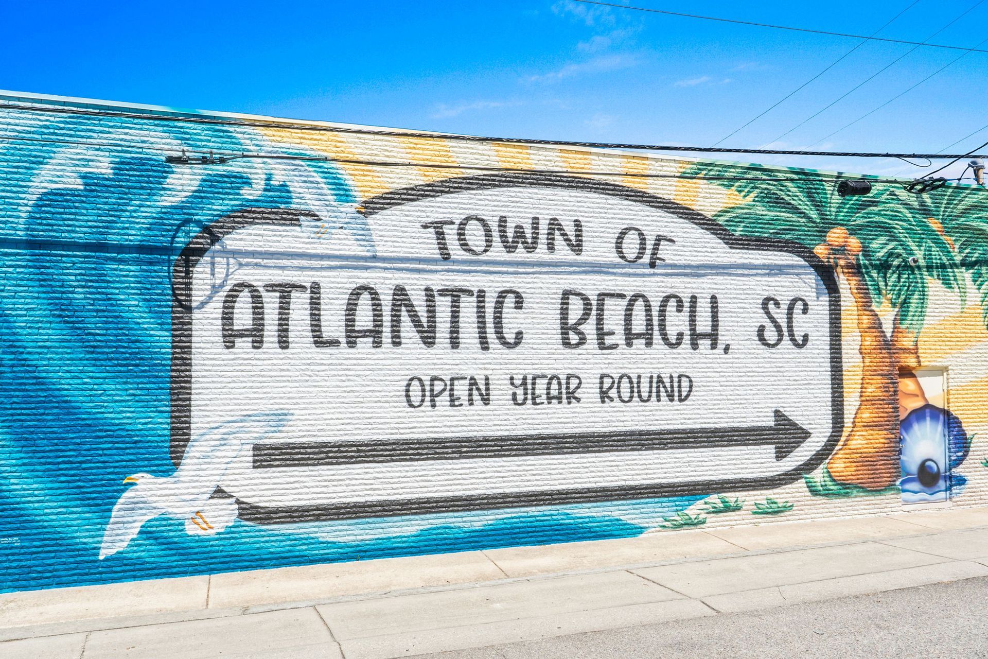 Murals on a wall reading “Town of Atlantic Beach, SC” with ocean-themed artwork and a dolphin
