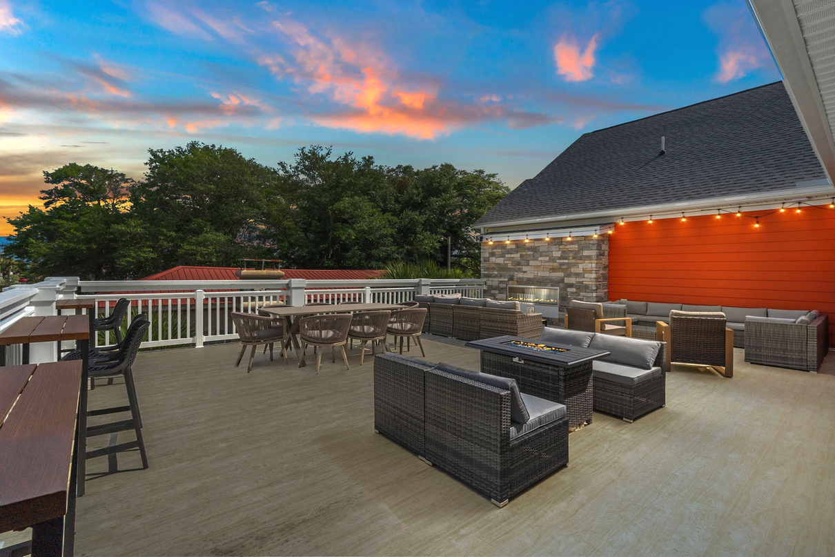 Rooftop patio with wicker seating, orange wall, and sunset sky over trees Atlantic Beach SC North Myrtle Beach SC airbnb with events weddings