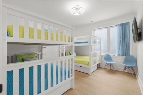 Bright shared children’s bedroom with two bunk beds, blue chairs, and a window desk