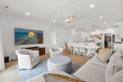 Bright open-plan living and dining room with white furniture, gray sofa, and coastal wall art