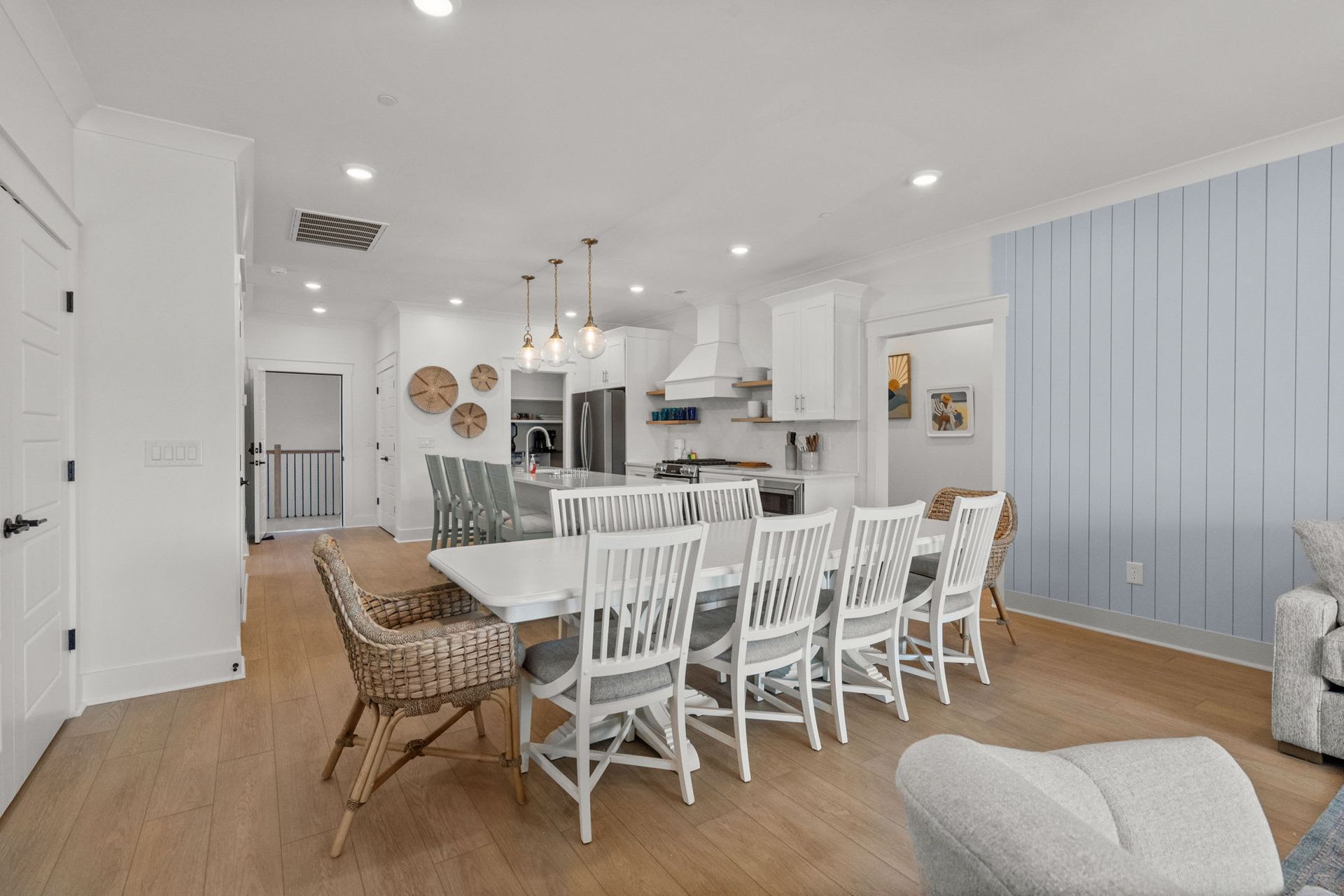 Bright dining room with white chairs, wood table, and pale blue paneled wall