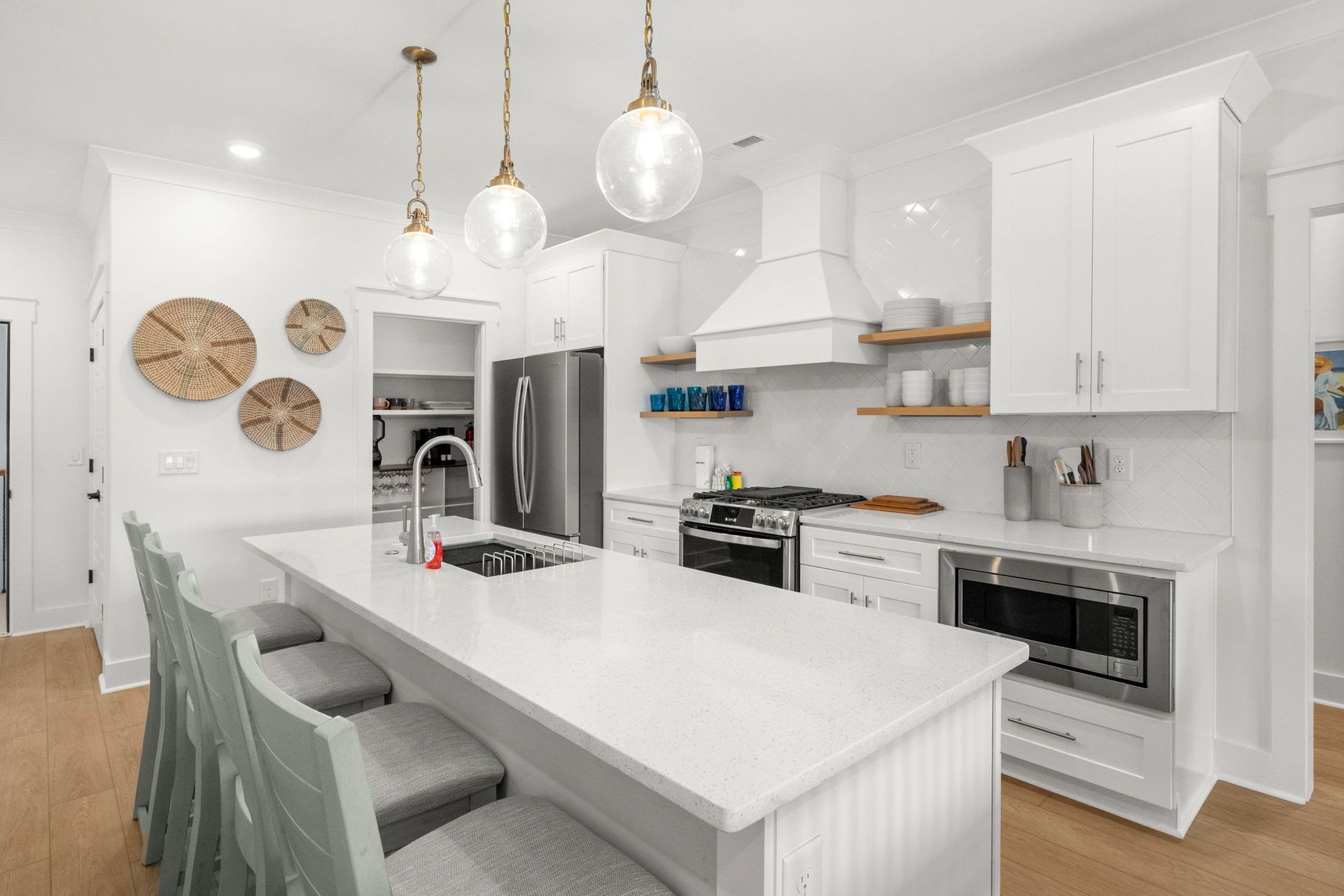 Bright modern kitchen with white cabinets, large island, stainless appliances, and pendant lights