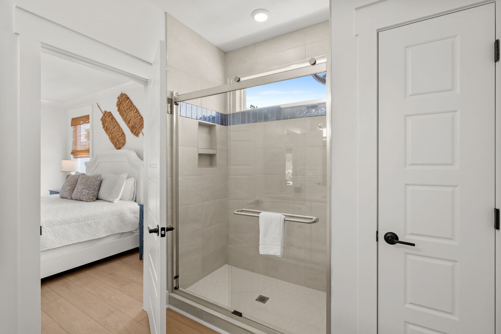 Bright bedroom view with glass shower, white doors, and light neutral walls