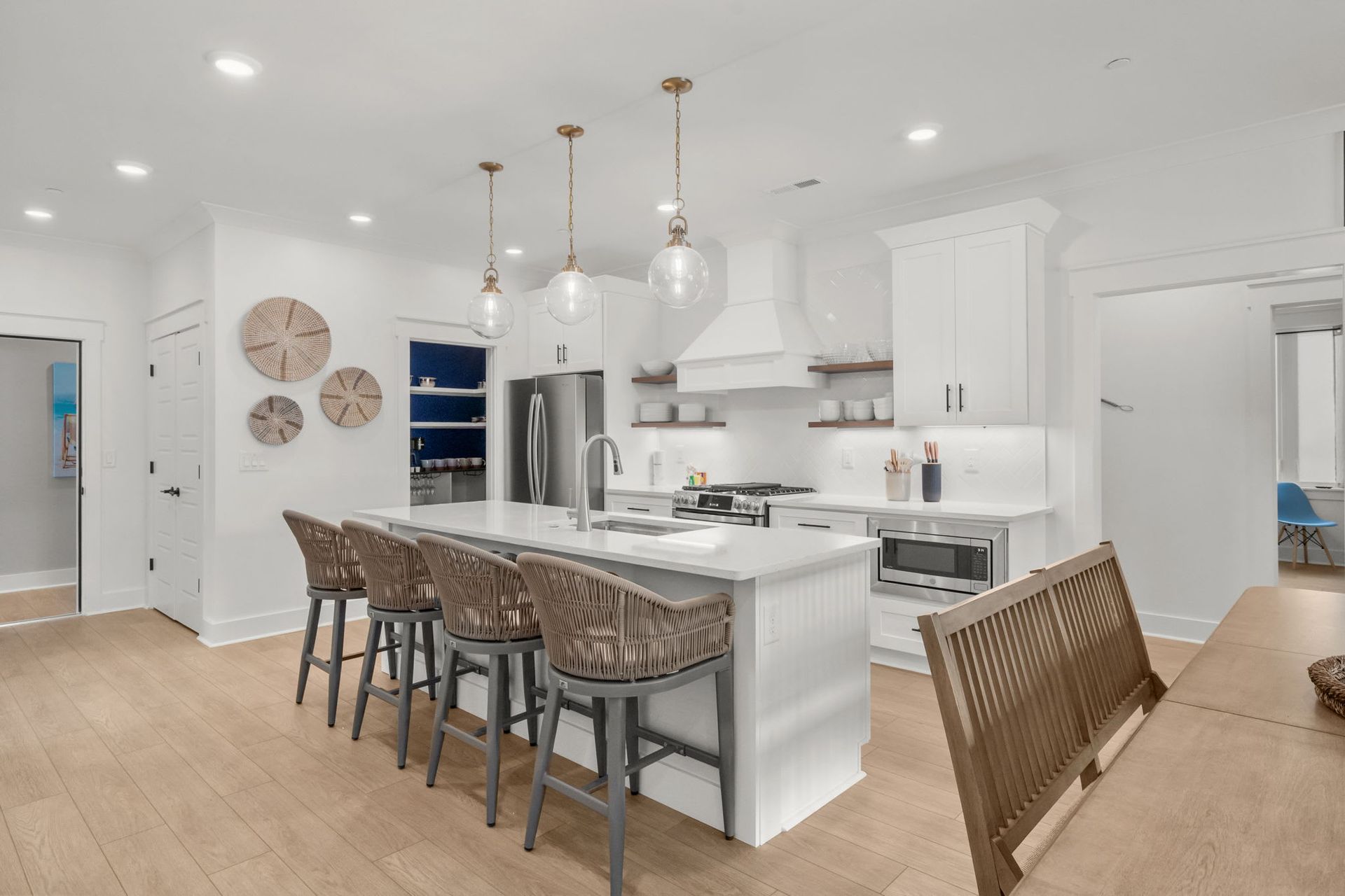 Bright white modern kitchen with island seating, pendant lights, and light wood floors