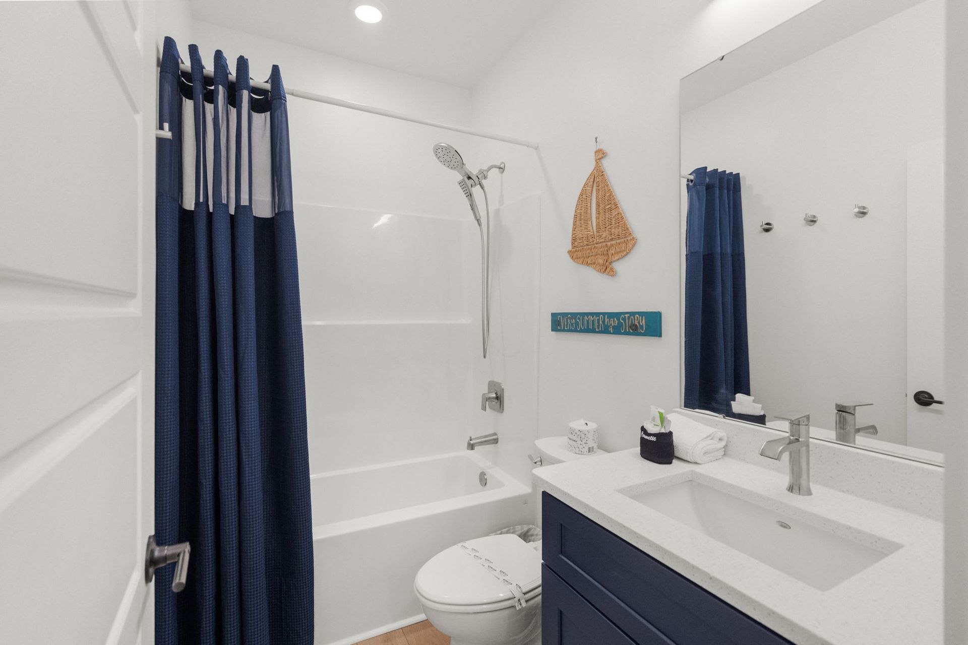 Bright bathroom with navy shower curtain, white tub, and vanity sink