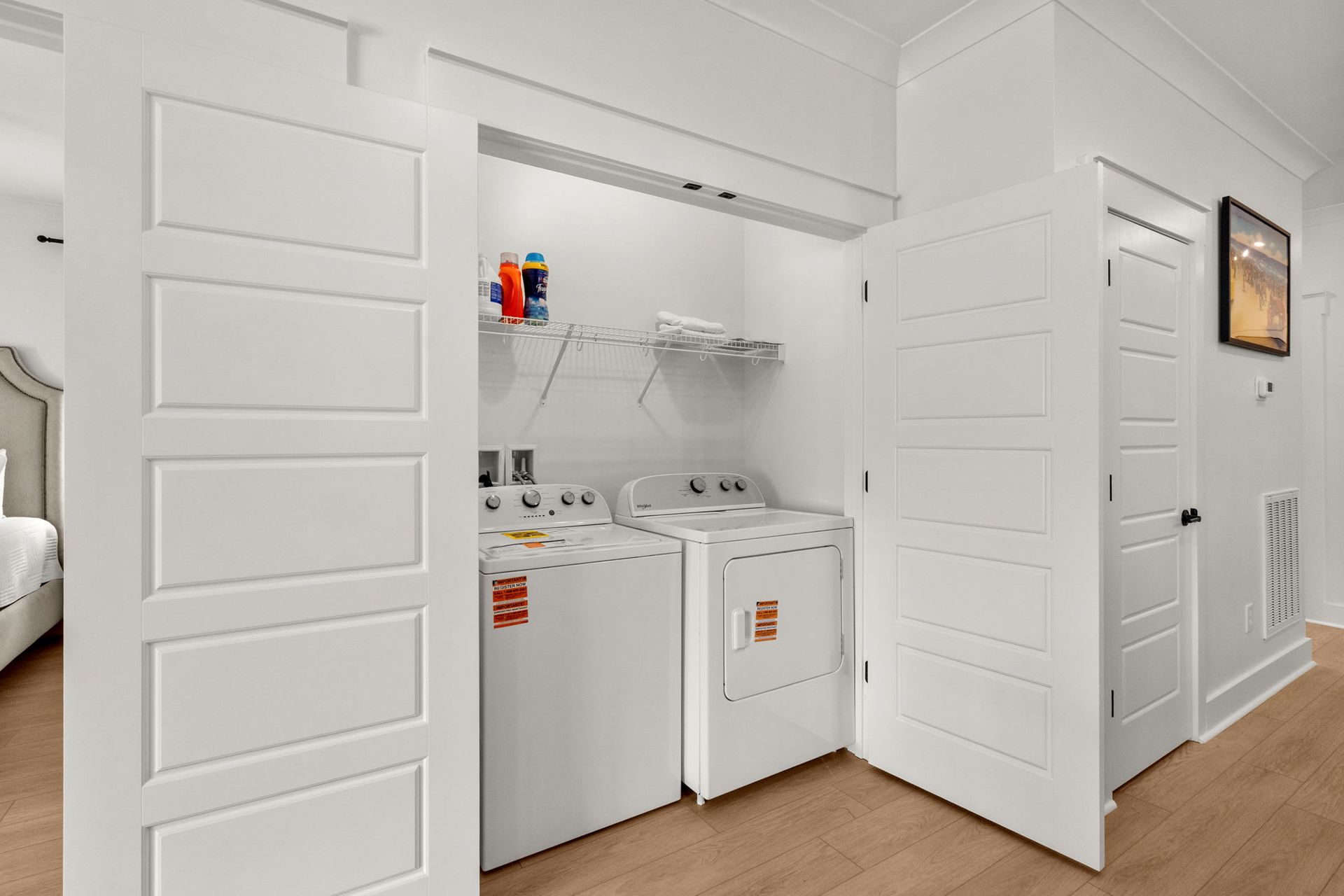 Open closet with stacked washer and dryer in a bright white laundry area