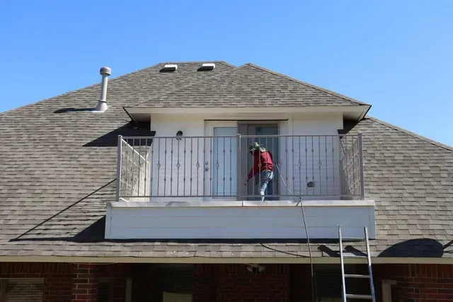 A man is standing on a balcony of a house.
