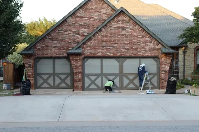 A brick house with a garage door that has the letter x on it