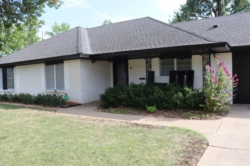 A white brick house with a black garage door and a gray roof.