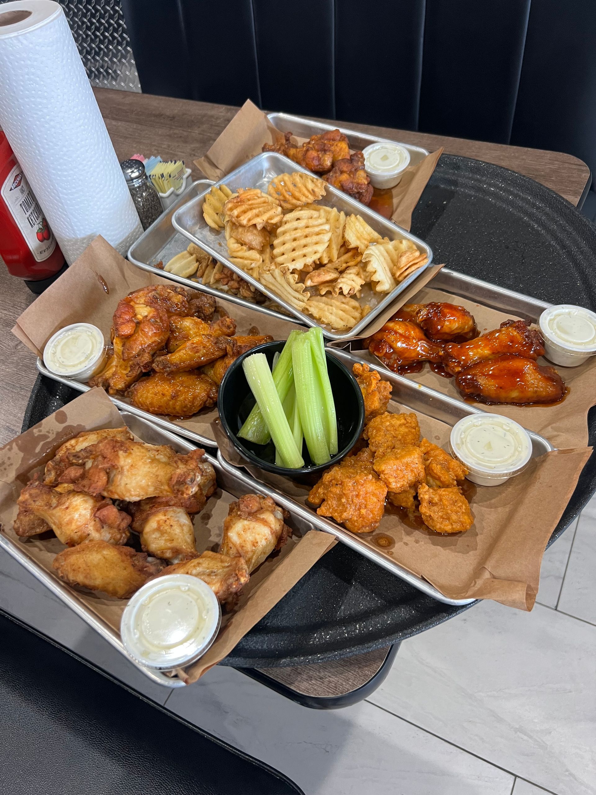 Buffet of fried chicken, waffle fries, and celery with dipping sauces on a table