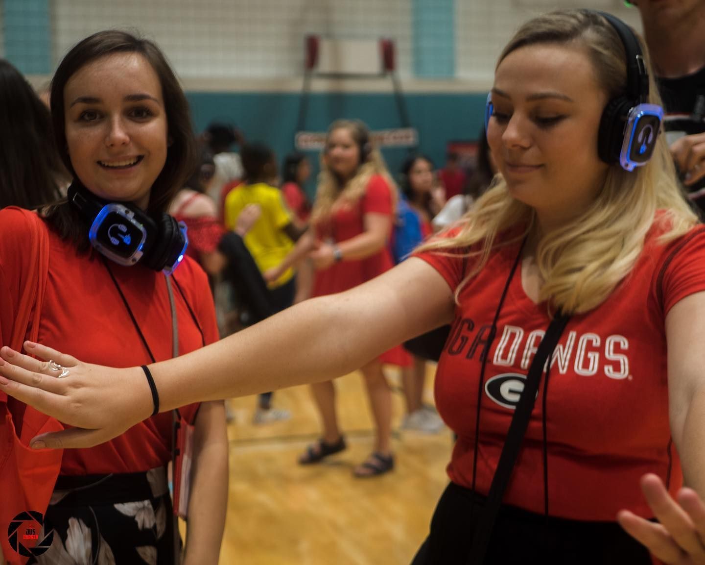 Two girls wearing headphones and red shirts with g on them