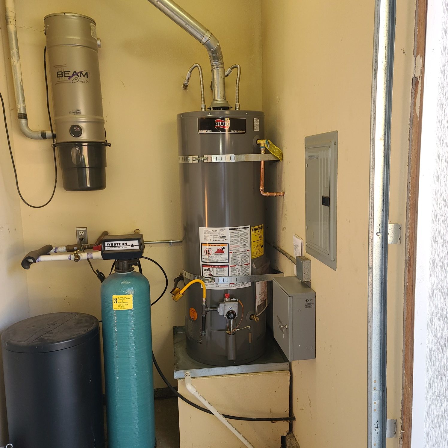 A utility room with a water heater, water softener, and central vacuum unit.