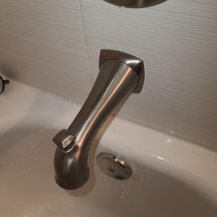 Brushed nickel bathtub faucet with a diverter in a white bathtub.