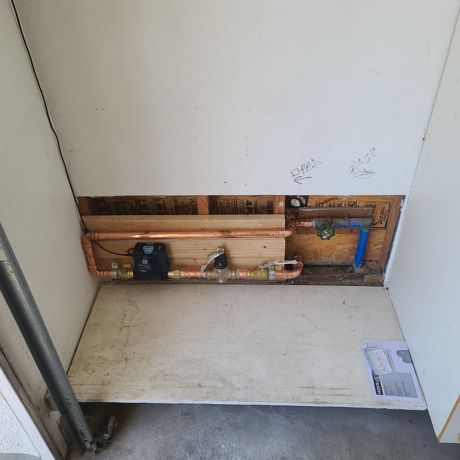 Plumbing system installed in a recessed wall. Copper pipes and black valve are visible.