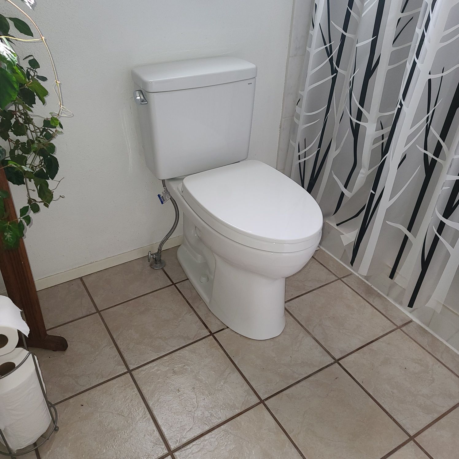 White toilet in a bathroom, with a closed lid, against a white wall and tile floor