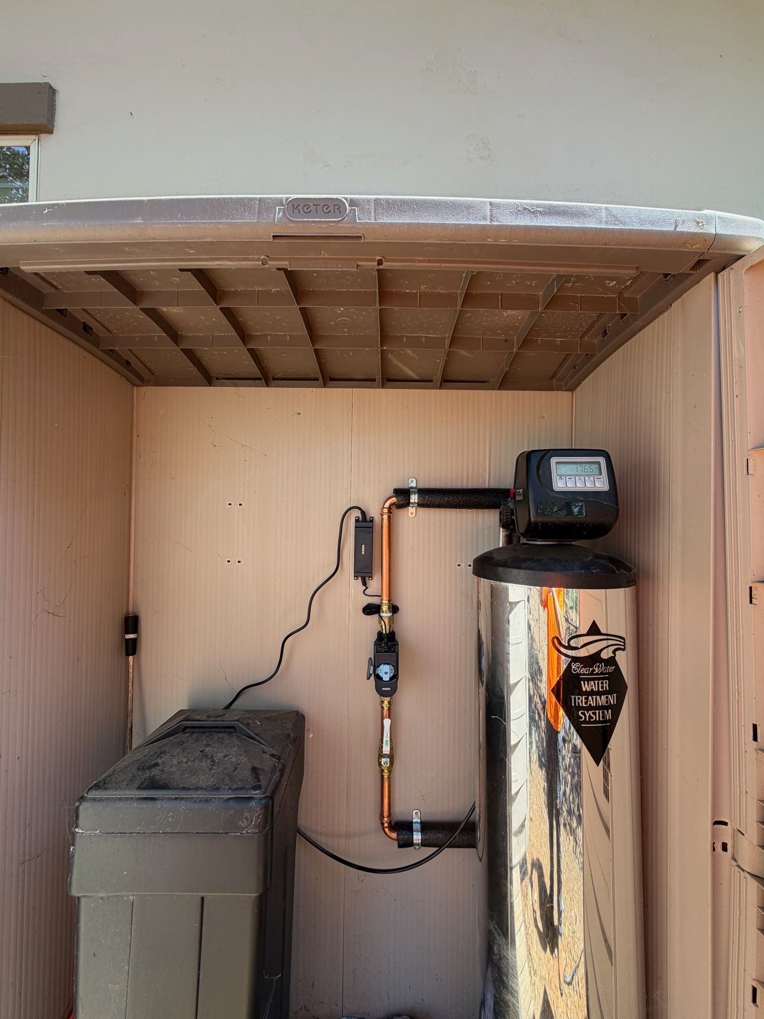 Wood-paneled shed interior with a furnace, water heater, and utility equipment along the back wall.