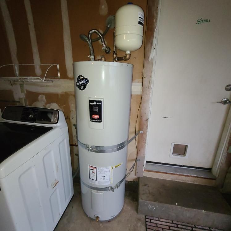 White water heater with expansion tank in a utility room next to a washing machine and door.