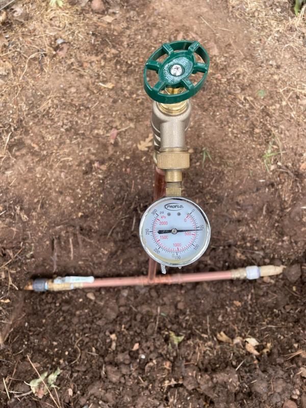 A water pressure gauge and valve system in a dirt trench, for irrigation use.