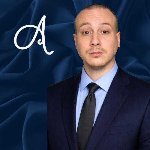 Man in a navy suit on a blue satin background with a white cursive letter A.