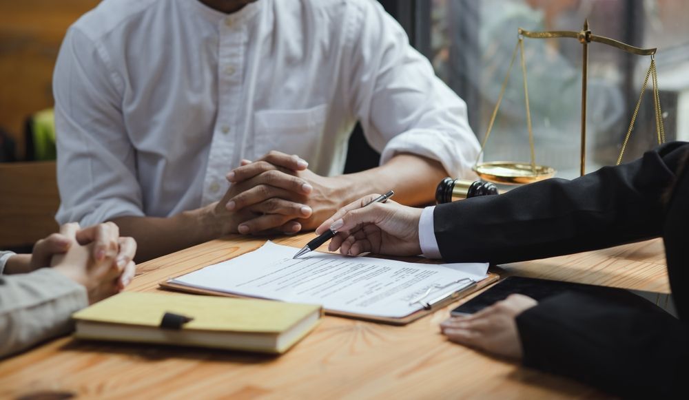 Business meeting with hands over documents on a wooden table and a brass scale in the background