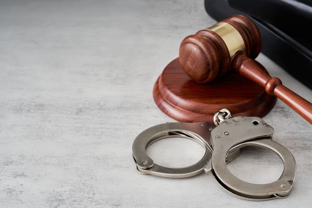 Handcuffs beside a judge’s gavel on a desk, symbolizing a legal arrest or crime case