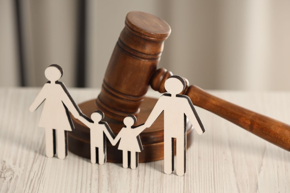 Paper family figures beside a gavel, symbolizing child custody or family law in court
